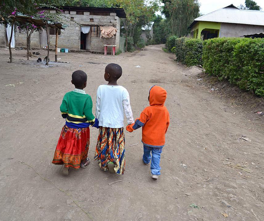 Tanzanianske barn går til skolen mens de holder hender